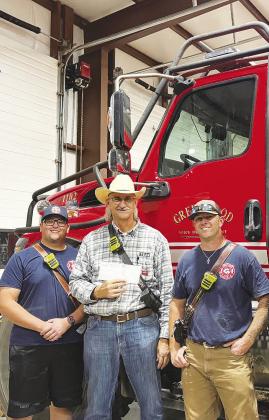 Greenwood firefighters proudly hold a $4,200 donation check from the Steven Smithhart Memorial Foundation, a nonprofit that raises funds in honor of Steven Smithhart, who died in a vehicle accident. The foundation, supported by Smithhart's family, recently hosted its annual fundraiser at Rooster’s Backyard, with proceeds going to GVFD.
