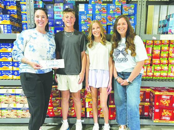 Brooks Middle School GT students Brock Hughes and Hannah Bridges present a $1,000 donation to Rangers Outreach organizers, raised through their basketball tournament passion project.