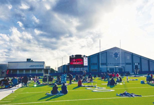 Families spread out blankets and lawn chairs across the turf 