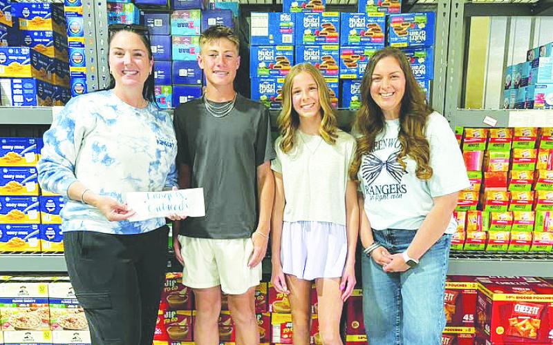 Brooks Middle School GT students Brock Hughes and Hannah Bridges present a $1,000 donation to Rangers Outreach organizers, raised through their basketball tournament passion project.