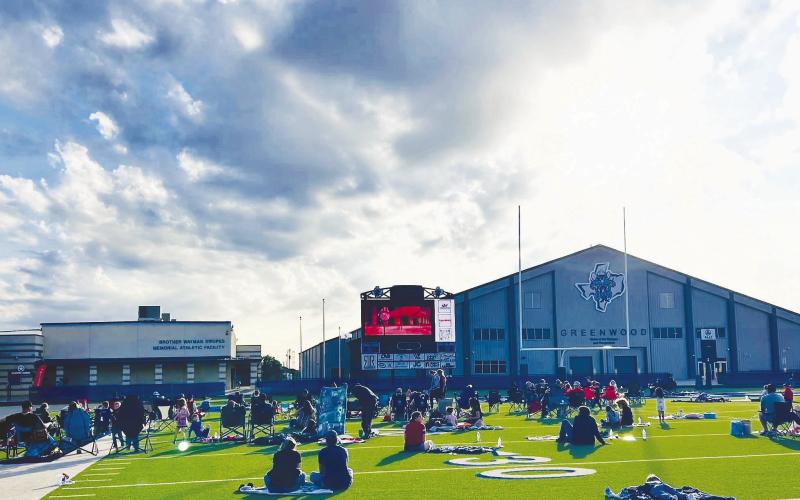 Families spread out blankets and lawn chairs across the turf