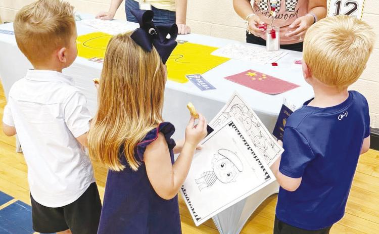 Incoming kindergarten students get their passports stamped at the China booth during Greenwood Elementary’s “Rangers Take Flight” orientation.
