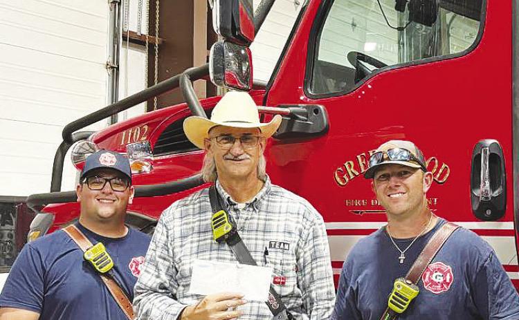 Greenwood firefighters proudly hold a $4,200 donation check from the Steven Smithhart Memorial Foundation, a nonprofit that raises funds in honor of Steven Smithhart, who died in a vehicle accident. The foundation, supported by Smithhart's family, recently hosted its annual fundraiser at Rooster’s Backyard, with proceeds going to GVFD.