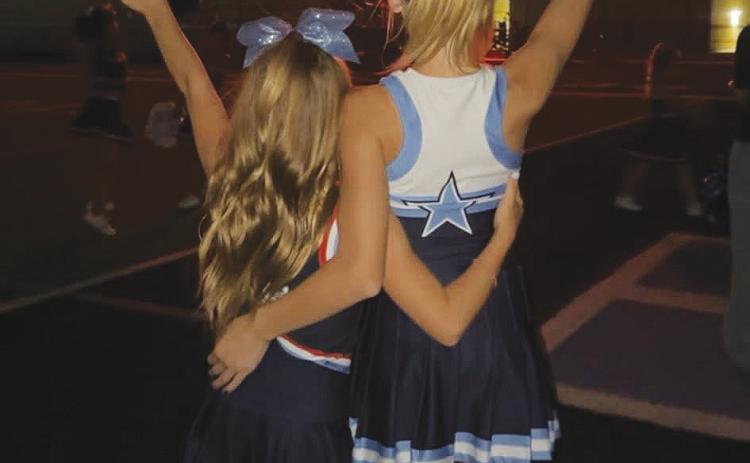 Youth cheerleaders Kynzli and Brantlee pose with their “guns up” during the fireworks show at Sunday’s homecoming tailgate.