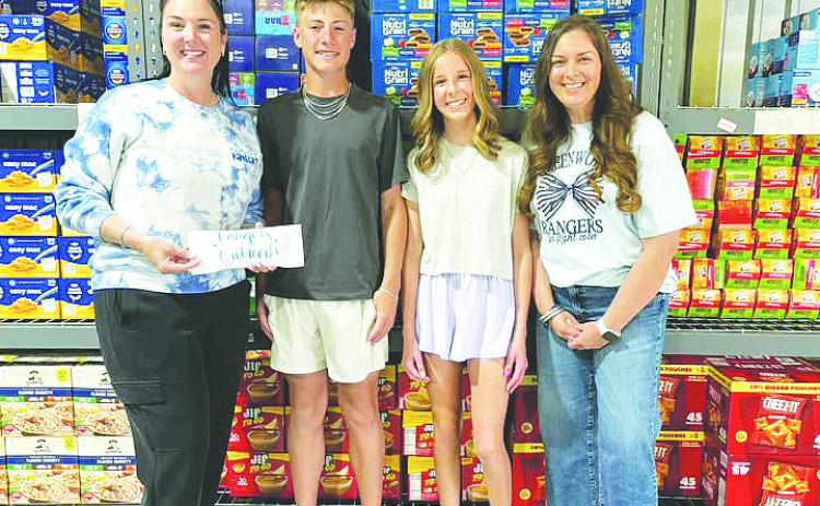 Brooks Middle School GT students Brock Hughes and Hannah Bridges present a $1,000 donation to Rangers Outreach organizers, raised through their basketball tournament passion project.