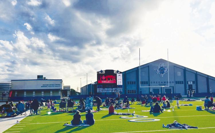 Families spread out blankets and lawn chairs across the turf